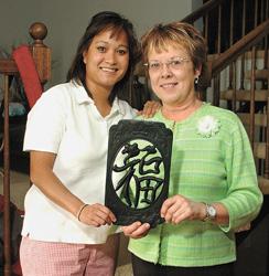 Nicole Barth and her mother Sandy Enget hold a lettered wall hanging representing prosperity.