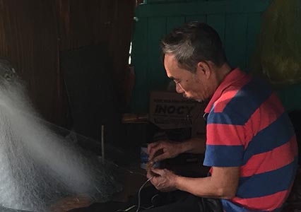 Fisherman fixes his net in Vietnam